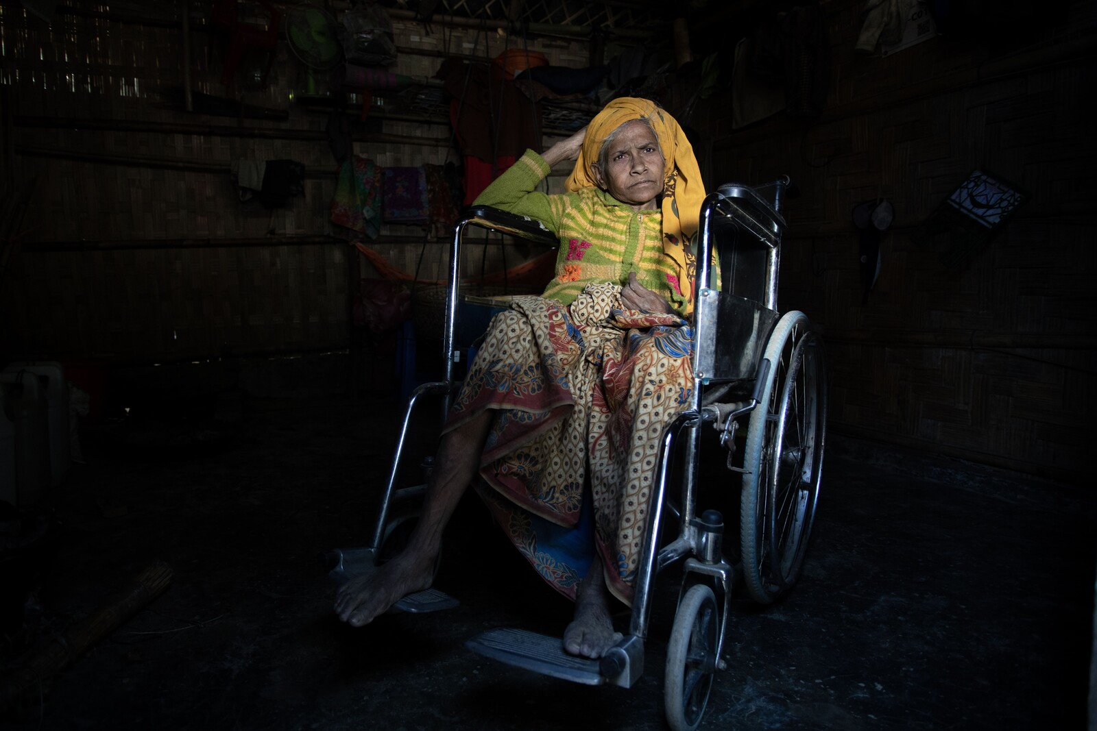 Suriya Khatun rests on her wheelchair as a few rays of light comes from outside her shelter. (Mushfiqul Alam/Oxfam)