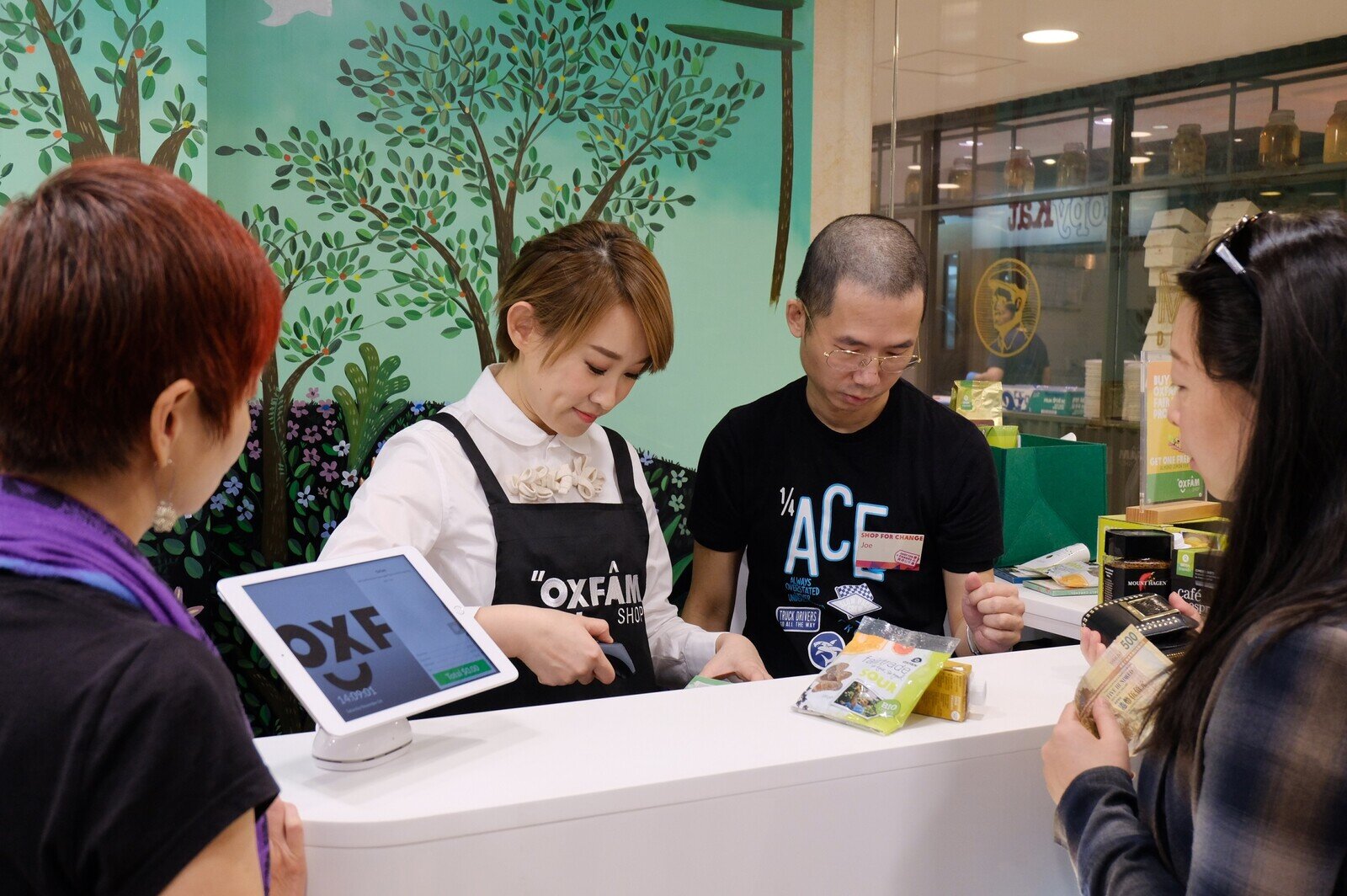 樂施商店同事向王菀之解說收銀工作須知事項