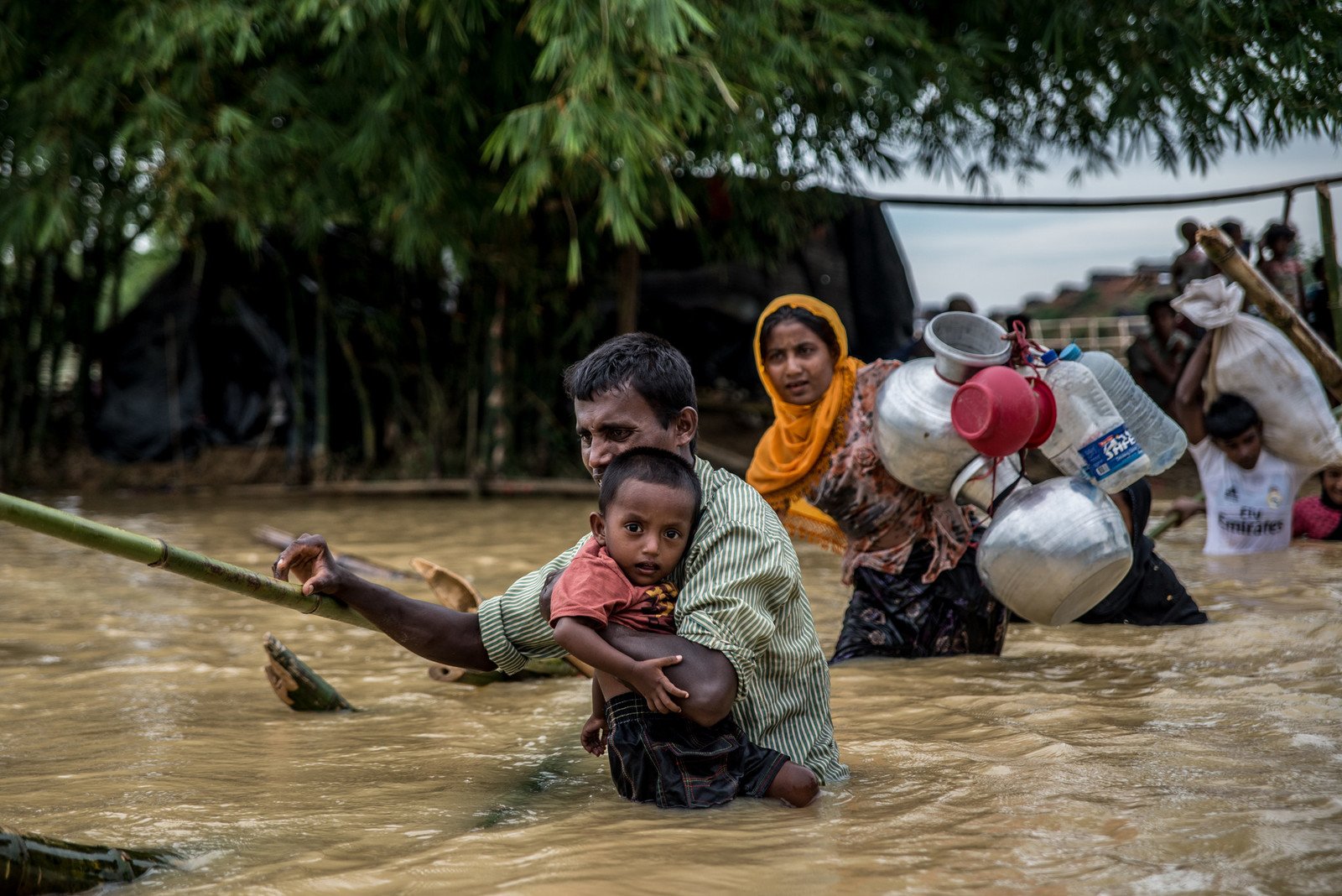 Balakhali难民营位于孟加拉境内，一名抱著儿子的父亲，正利用破烂的竹桥渡过这条位于难民营附近的河流。连续三天的大雨令许多难民临时栖身所出现水浸，迫使他们迁往地势更高的地方。 photo: Aurélie Marrier d'Unienville