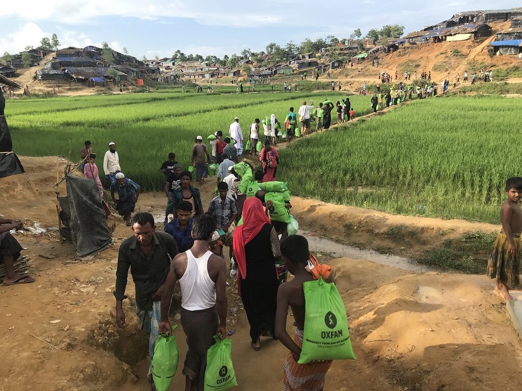 People walking through a field with the relief they received from Oxfam.