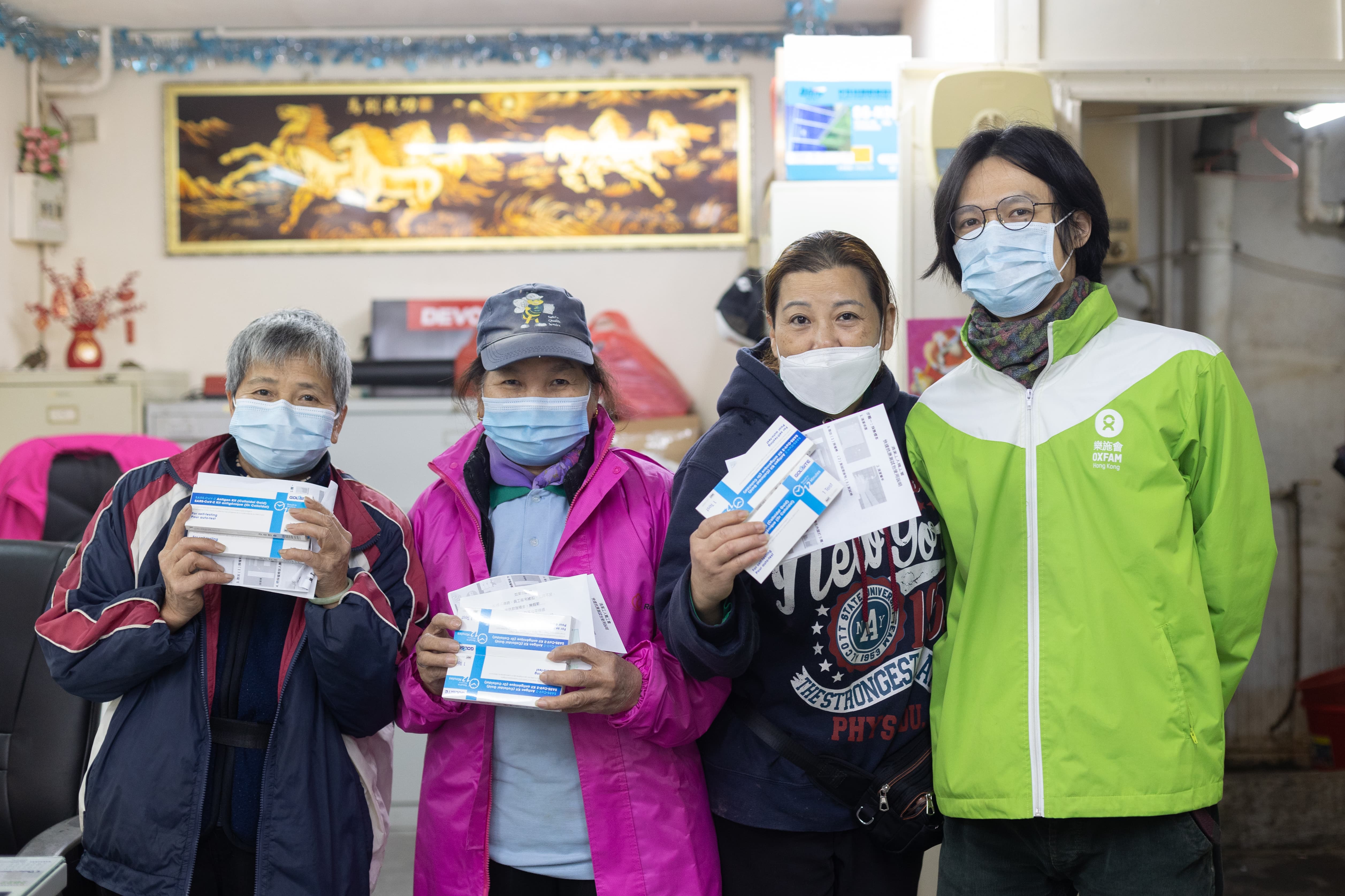 Outsourced cleaners holding test kits standing next to Oxfam staff